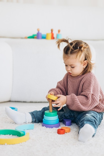 Cute little toddler girl playing at home with eco wooden toys Happy child cutting vegetables and fruits with toy knife The child playing educational games