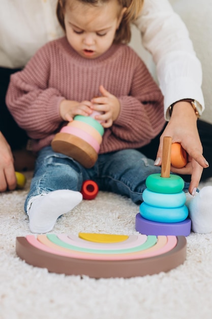 Cute little toddler girl playing at home with eco wooden toys Happy child cutting vegetables and fruits with toy knife The child playing educational games