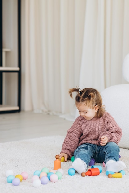 Cute little toddler girl playing at home with eco wooden toys Happy child cutting vegetables and fruits with toy knife The child playing educational games