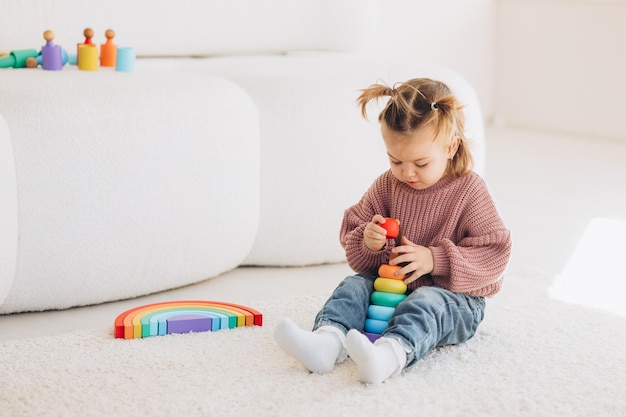 Cute little toddler girl playing at home with eco wooden toys Happy child cutting vegetables and fruits with toy knife The child playing educational games