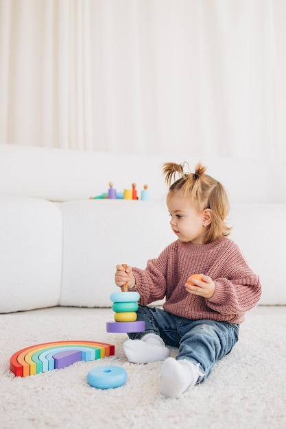 Cute little toddler girl playing at home with eco wooden toys Happy child cutting vegetables and fruits with toy knife The child playing educational games