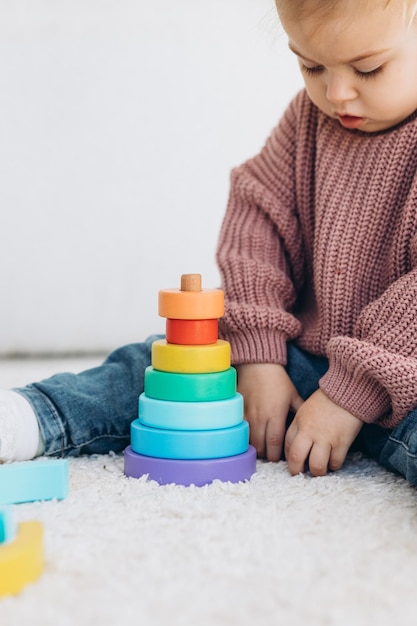 Cute little toddler girl playing at home with eco wooden toys Happy child cutting vegetables and fruits with toy knife The child playing educational games