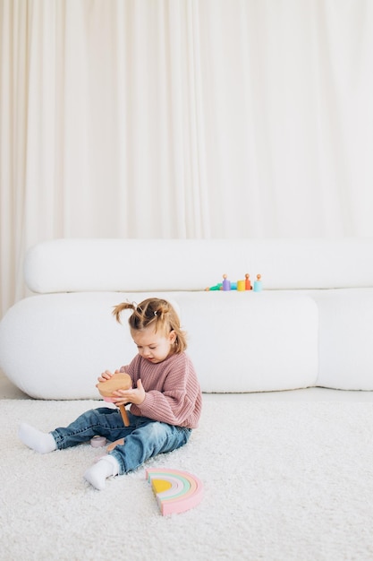 Cute little toddler girl playing at home with eco wooden toys Happy child cutting vegetables and fruits with toy knife The child playing educational games