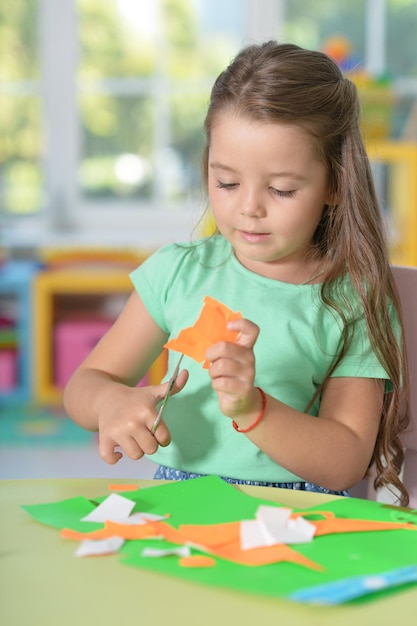 Cute llittle girl is cutting color paper