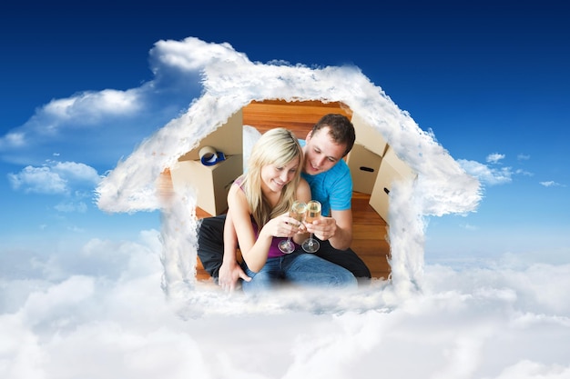 Cute lovers celebrating new house with champagne against bright blue sky with clouds