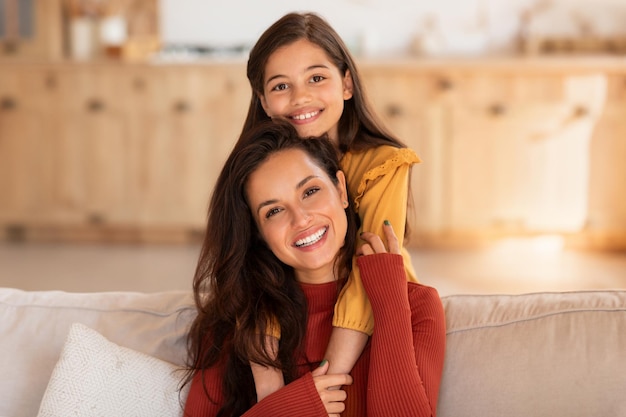 Cute middle eastern girl hugging mommy from back at home