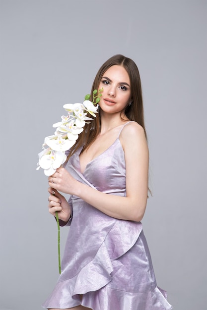 Cute model girl in dress with orchid flower Portrait with a beautiful face for advertising beautician services and makeup