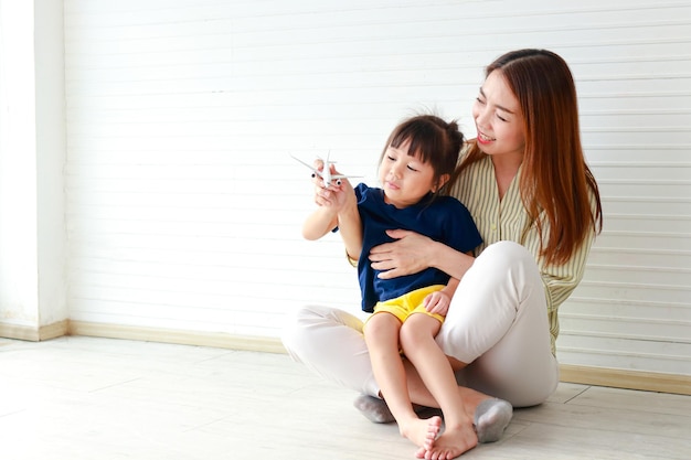 Cute mother and daughter Hugging and teasing each other sitting on the floor of the house Family concept single mother copy space