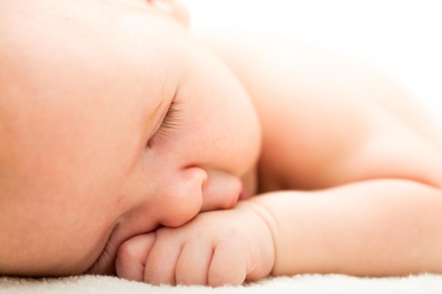 Cute newborn baby sleeping on bed, close up