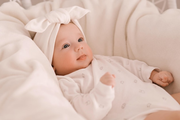 Cute newborn girl in white clothes on a light background