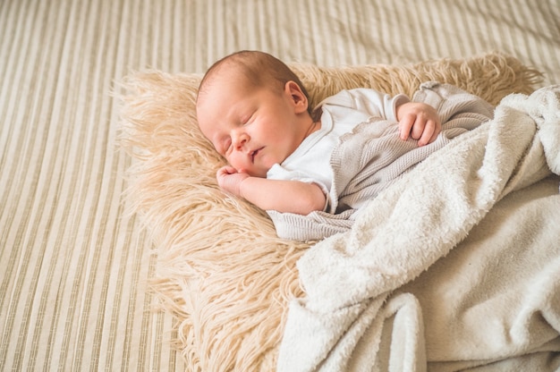 Cute newborn infant baby asleep wrapped in a soft  plaid. Love baby. Newborn baby and mother.