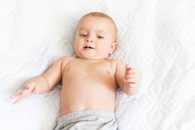 cute nine month old baby smiles with its first teeth. little boy is resting