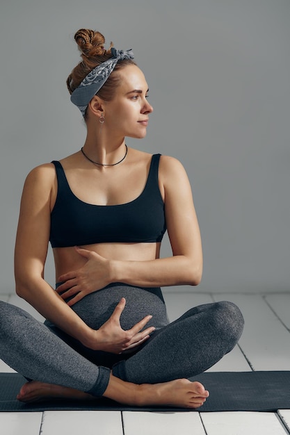 Cute pregnant belly isolated on gray Side view of young pregnant woman embracing her abdomen with hands Big belly on the third trimester of pregnancy closeup Concept of pregnant life