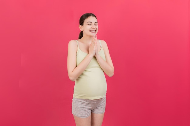 Cute pregnant woman praying on colored background isolated