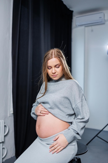 Cute pregnant woman in sweater and skirt with tummy Happy elegant pregnant woman A woman is expecting a child