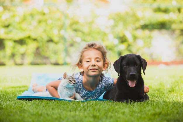 Cute preschool girl play with pets on fresh grass