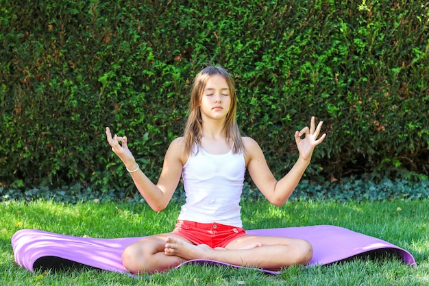 Cute preteen girl practicing yoga outdoors in the garden 