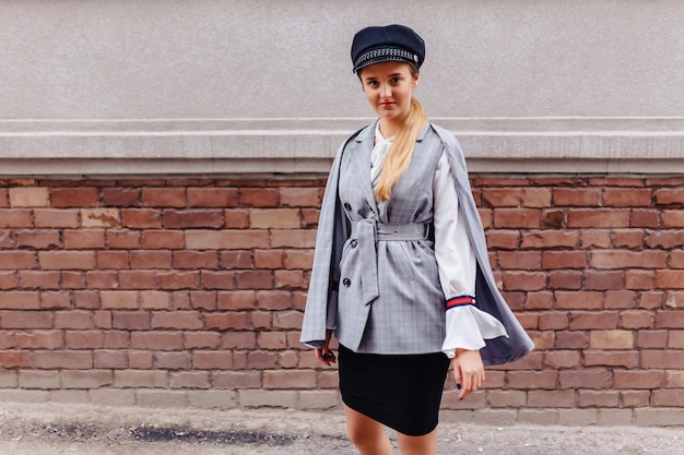 A cute, pretty girl in a stylish suit walks around the city and poses