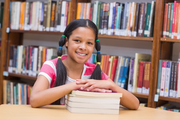 Cute pupil looking at camera in library 