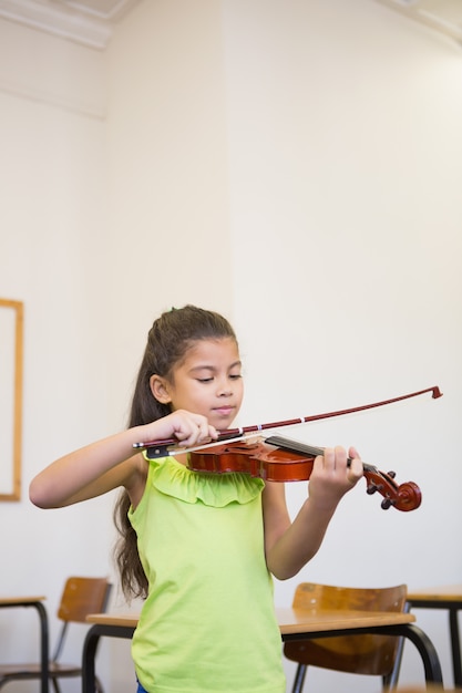 Cute pupil playing violin in classroom at the elementary school