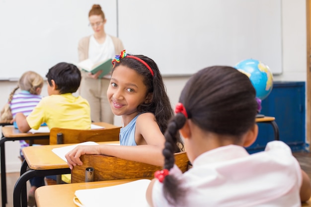 Cute pupil smiling at camera in classroom