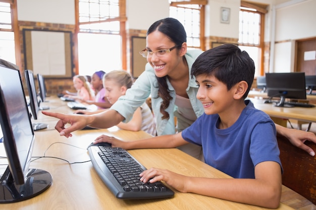 Cute pupils in computer class with teacher at the elementary school