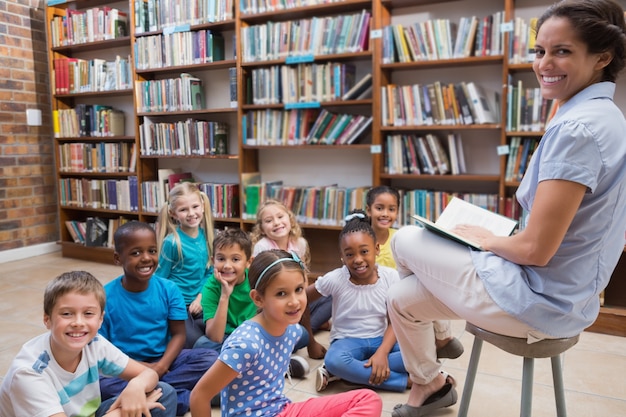 Cute pupils sitting on floor in library