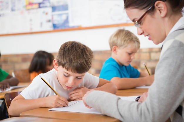 Cute pupils writing at desk in classroom