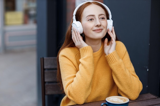 cute red hair woman in headphones outdoor in casual wear