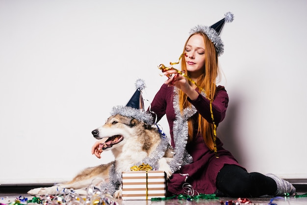 Cute red-haired girl sits on the floor with her dog and celebrates the new year 2018