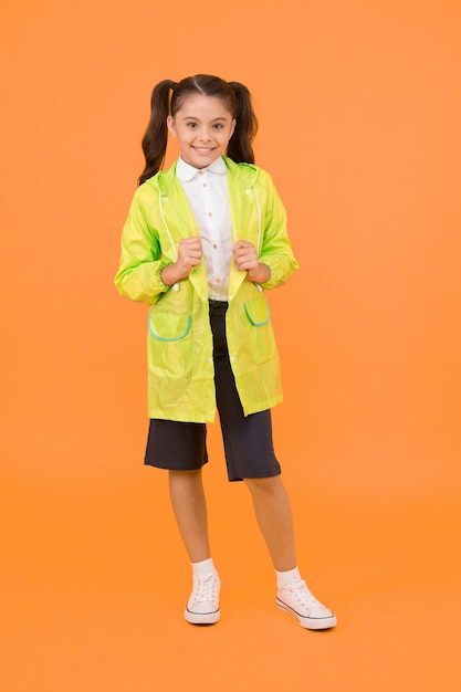 Cute schoolgirl feel protected. Happy schoolgirl wear raincoat. Invest in durable kids rainwear to keep children out in fresh air. Waterproof concept. Small schoolgirl wear water resistant clothes.