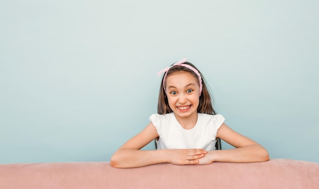 Cute schoolgirl girl smiling closeup on a blue background