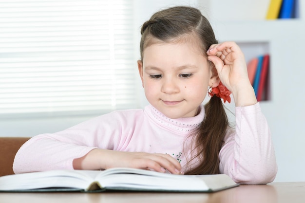 Cute schoolgirl sitting at table and doing homework