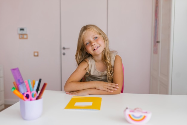 Cute sevenyearold girl is sitting at a desk in a classroom at school