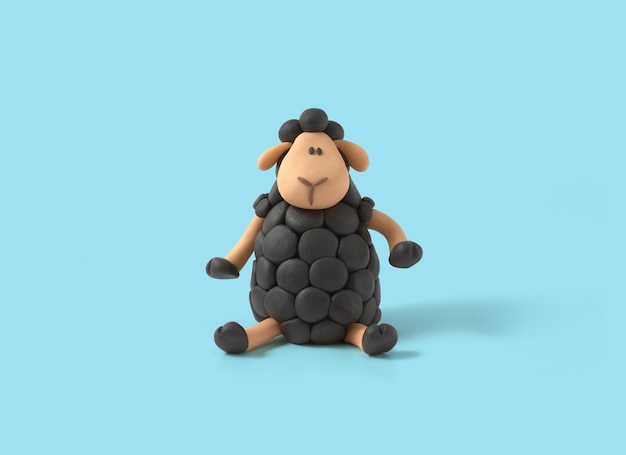 Cute sitting black sheep made of plasticine on blue background Clay sheep outstanding different