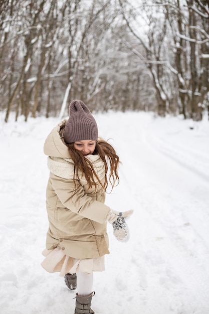 a cute sixyearold girl throws a snowball at the camera on a walk in a snowy forest in winter