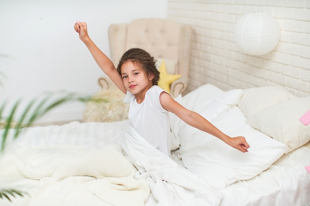 Cute sleepy baby girl, stretches, hands up, after sleeping in the morning