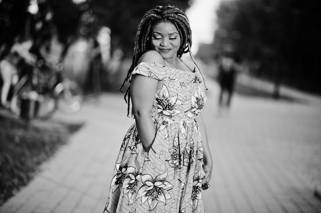 Cute small height african american girl with dreadlocks wear at coloured yellow dress posed at sunset Black and white