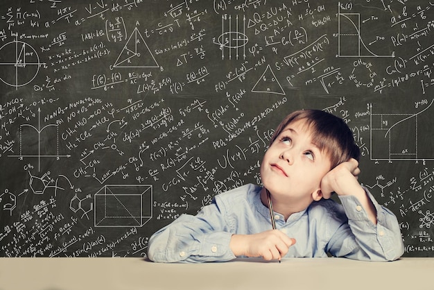 Cute smart child student on blackboard background with science formulas Learning science concept