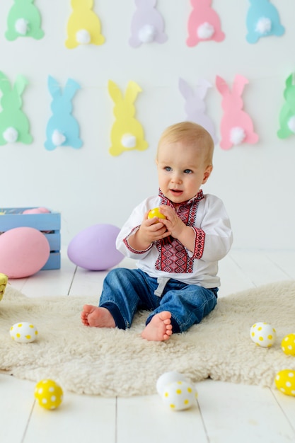 Cute smiling baby in traditional embroidery in colored Easter decorations