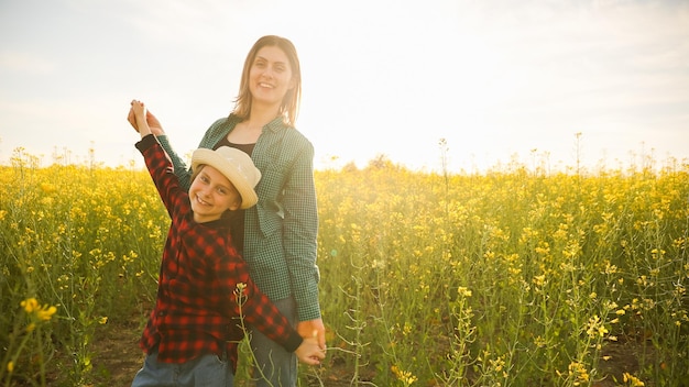 Cute smiling caucasian farmer family mother and child standing in a flowering rapeseed happy kid and