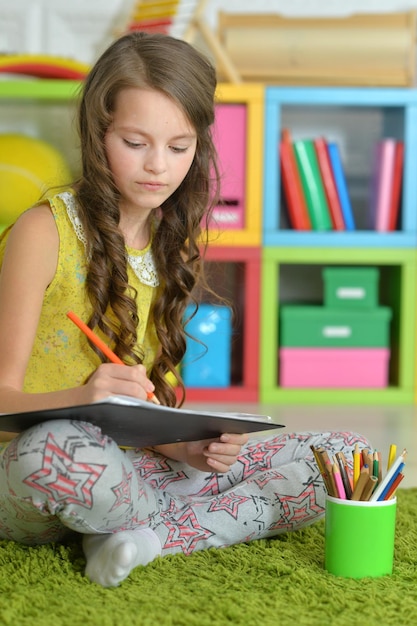 Cute smiling girl drawing at home