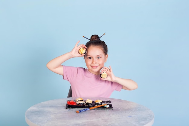 Cute smiling little girl with with sushi on red background Student child girl eating sushi and rolls commercial concept