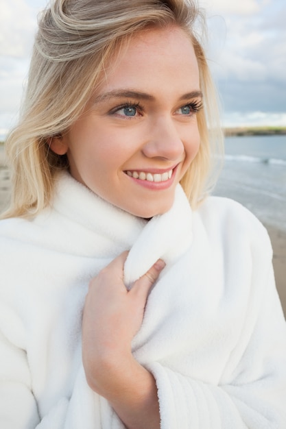 Cute smiling woman in stylish white jacket on beach