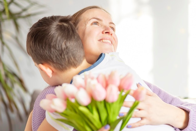 Cute son giving his mother bouquet of tulips congratulating her on mothers day