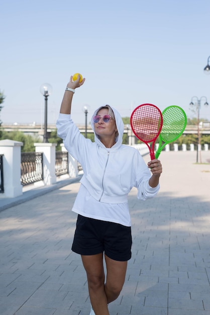 A cute sporty woman is holding racket and ball outdoor