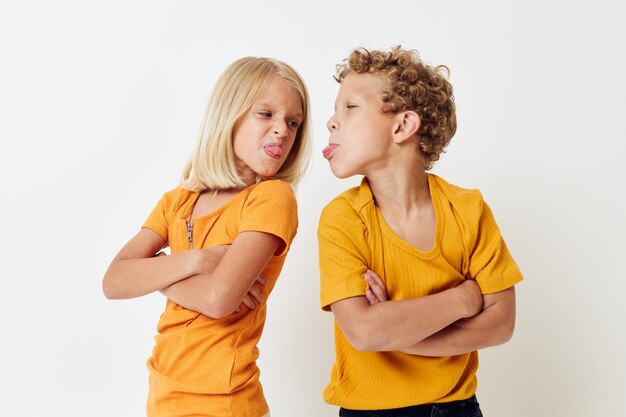 Cute stylish kids in yellow tshirts standing side by side childhood emotions light background unaltered