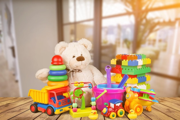 Cute teddy bear and bright toys on wooden table