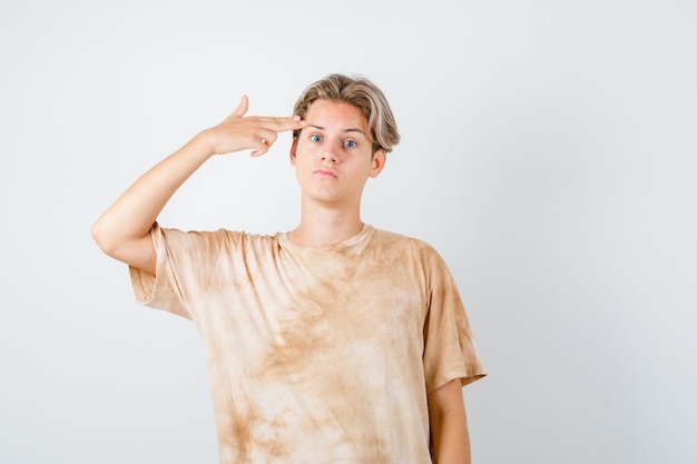 Cute teen boy showing suicide gesture in t-shirt and looking depressed , front view.