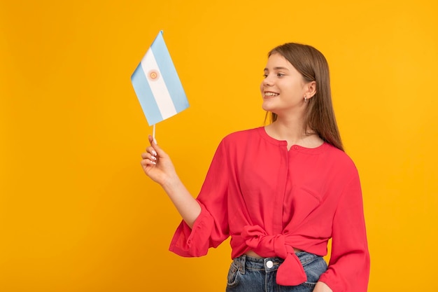 Cute teenage girl holds the flag of Argentina on orange background Youth in Argentina Travel to South America